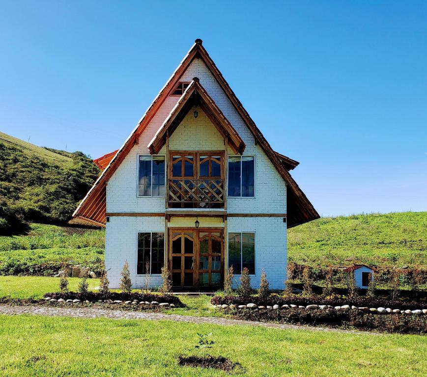 a house with a gambrel roof on a grass field at Finca Masada in Mira