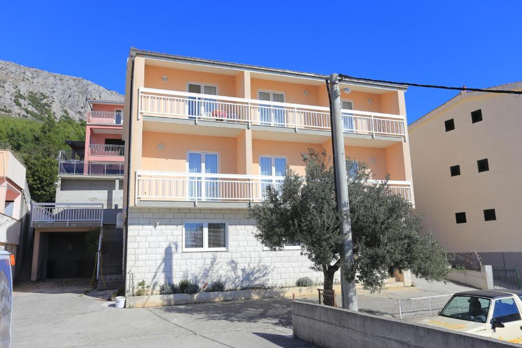 een appartementencomplex met een boom ervoor bij Apartments with a parking space Stanici, Omis - 2818 in Tice