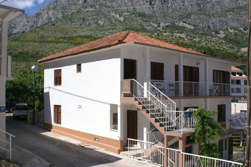 um edifício branco com escadas em frente a uma montanha em Studio Drvenik Donja vala 2732c em Drvenik