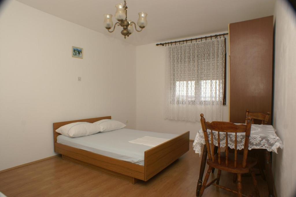 een slaapkamer met een bed, een tafel en een stoel bij Apartments by the sea Orij, Omis - 2810 in Dugi Rat