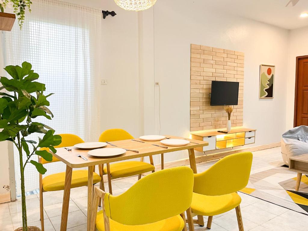 a dining room with a table and yellow chairs at H&Q 1BR Cozy House, Bangtao Beach in Ban Thalat Choeng Thale