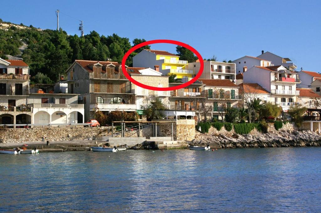 uma casa num círculo vermelho ao lado de uma massa de água em Apartments and rooms by the sea Milna, Hvar - 3074 em Hvar