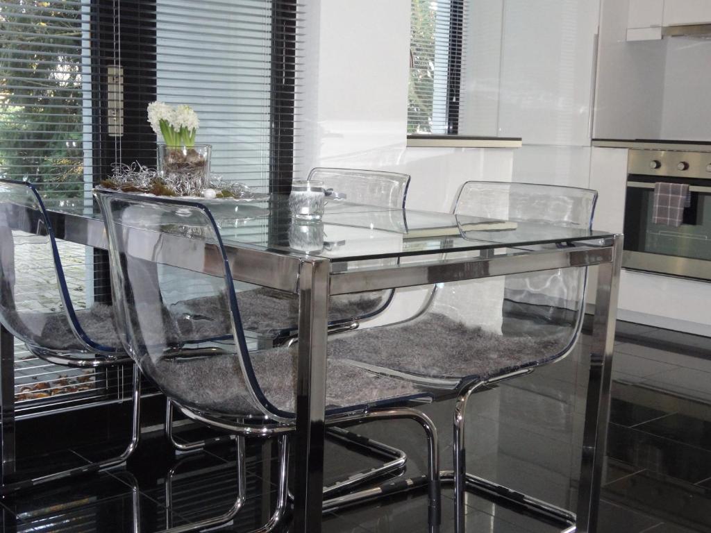 einen Esstisch aus Glas mit 4 Stühlen in der Küche in der Unterkunft Apartment Black & White Neuss in Neuss