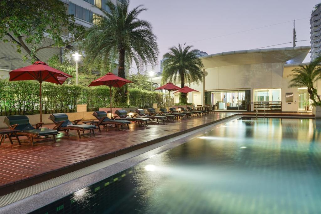 a pool with chairs and umbrellas in a hotel at Centre Point Sukhumvit Thong-Lo in Bangkok