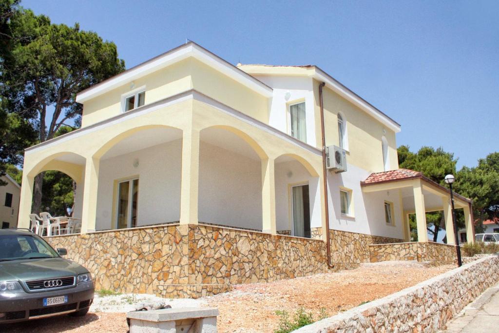 a white house with a stone wall at Double Room Rogoznica 3097a in Rogoznica