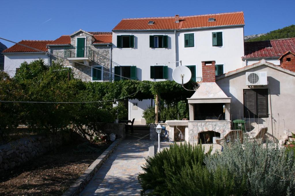 a large white building next to a house at Apartments with a parking space Bol, Brac - 4659 in Bol