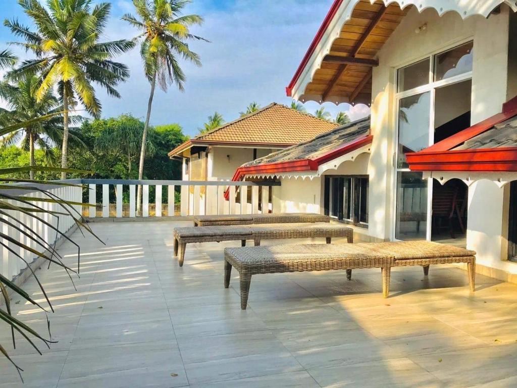 un patio avec bancs et un bâtiment avec palmiers dans l'établissement Rosanuka Beach Villa, à Wayikkal