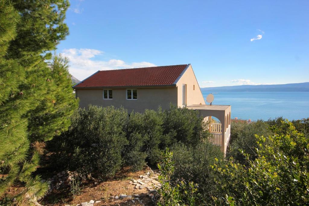une maison sur une colline avec l'océan en arrière-plan dans l'établissement Apartments with a parking space Duce, Omis - 4663, à Duće