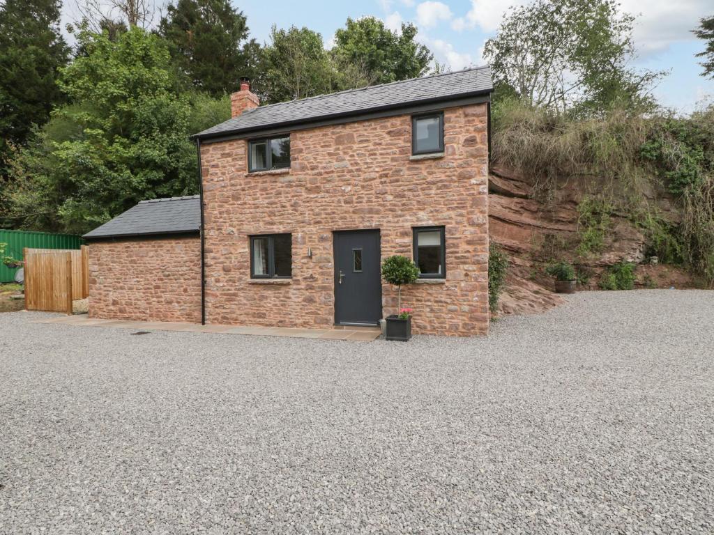 a brick house with a black door on a gravel driveway at The Old Mill Bake House in Ross on Wye