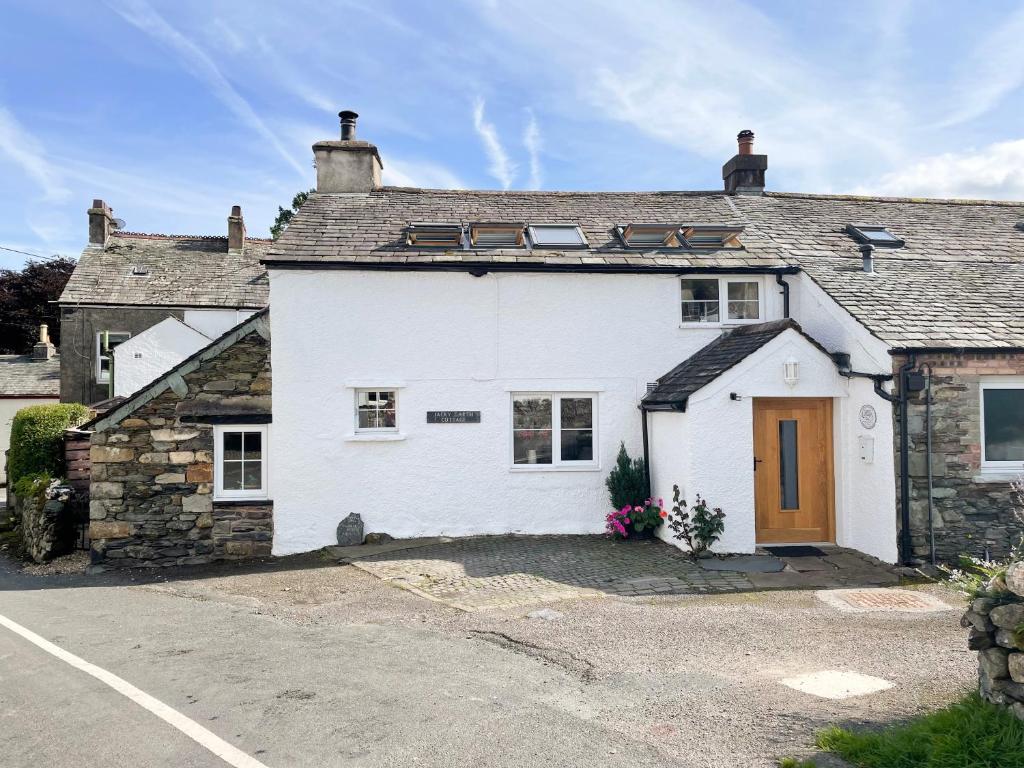 a white house with a driveway in front of it at Jacky Garth Cottage in Keswick