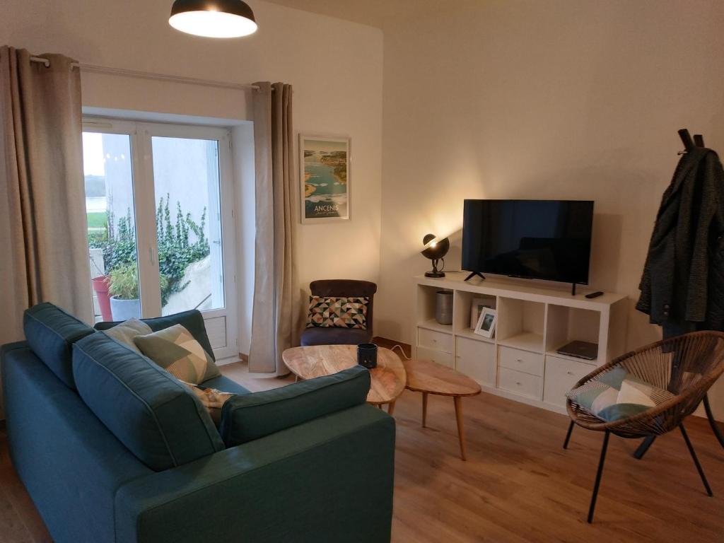 ein Wohnzimmer mit einem blauen Sofa und einem TV in der Unterkunft La maison du Bord de Loire in Ancenis