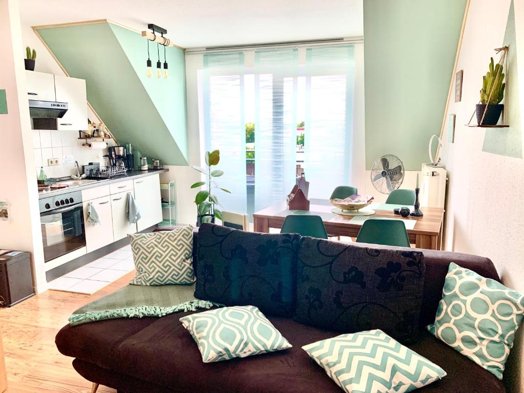 ein Wohnzimmer mit einem braunen Sofa und einer Küche in der Unterkunft Eigenes Apartment im Herzen der Stadt mit Balkon und WLAN in Cottbus