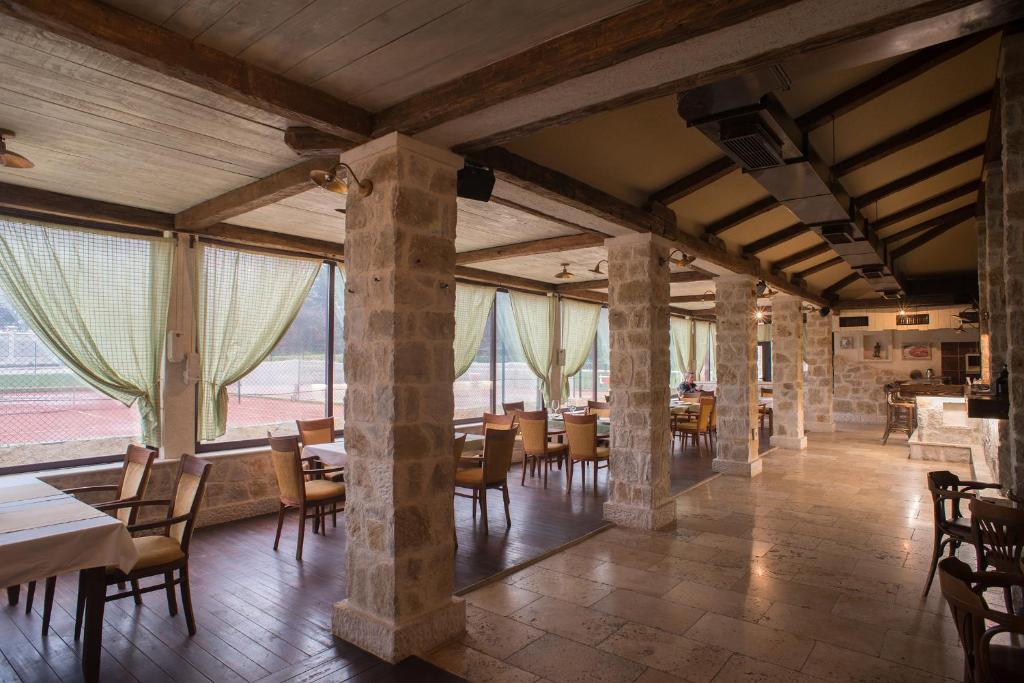 ein Esszimmer mit Tischen, Stühlen und Fenstern in der Unterkunft Hotel Trim in Nikšić