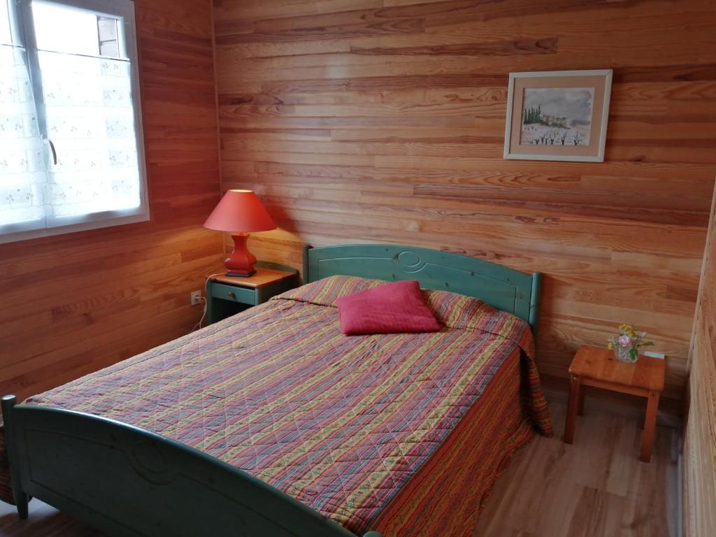 a bedroom with a bed with a red pillow on it at La petite maison dans la prairie 