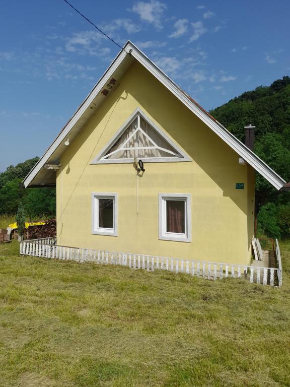 a yellow house with two windows in a field at Vikendica za odmor Raduša in Tešanj