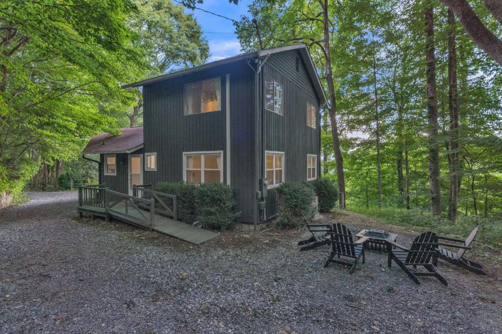 a black cabin in the woods with a table and chairs at Blue Ridge Lookout Beautiful Modern Cabin - Nature Hikes and Pets OK cabin in Waynesville
