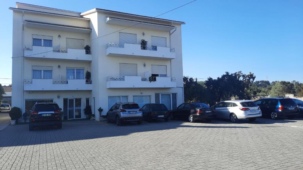 a white building with cars parked in a parking lot at Casa Talika in Fátima