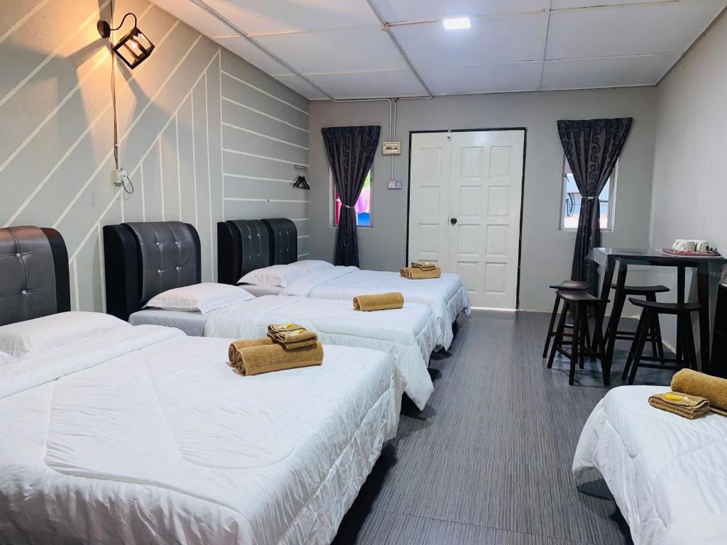 fila de camas en una habitación con mesa en Julies Hostel Taman Negara, en Kuala Tahan
