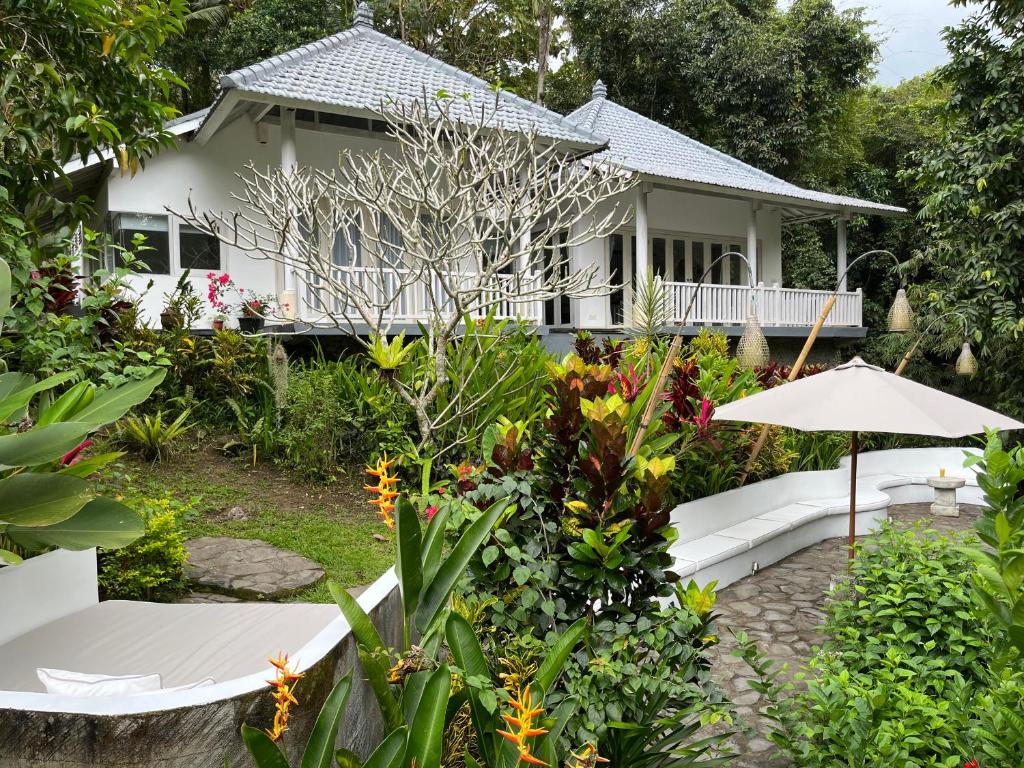 une maison avec un jardin et un parasol dans l'établissement Balian Bliss Retreat Resort Complex, à Balian