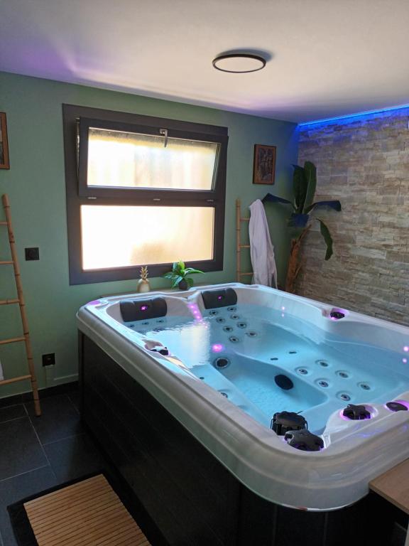 a large bath tub in a room with a window at Superbe appartement avec jacuzzi et extérieur in Perpignan