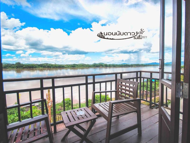 a balcony with two benches and a view of a river at Norn Nab Dao Rimkhong in Chiang Khan