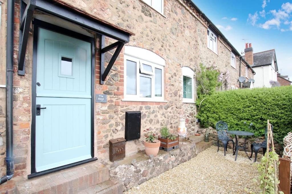 a brick house with a white door and a patio at Romantic & Cosy Cottage with Direct Access to the Hills in Malvern Wells