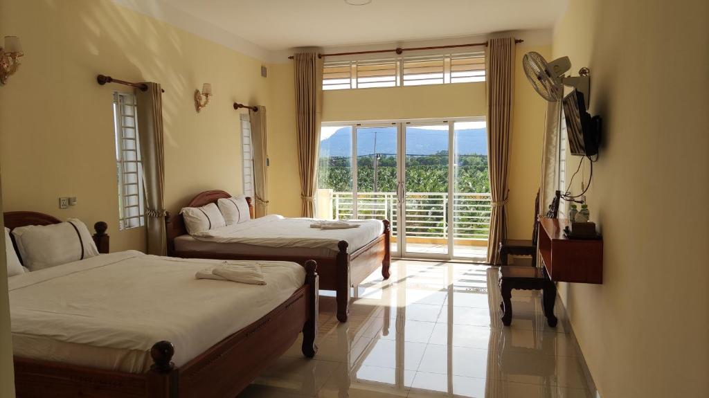 a bedroom with two beds and a large window at Monica Guesthouse in Kampot