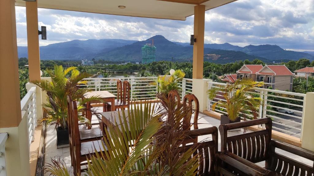 a balcony with tables and chairs and mountains in the background at Monica Guesthouse in Kampot