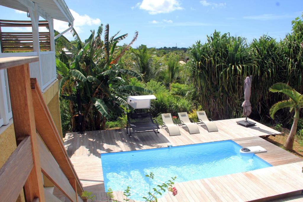 a swimming pool on a wooden deck with chairs at Villa Kajou in Sainte-Anne