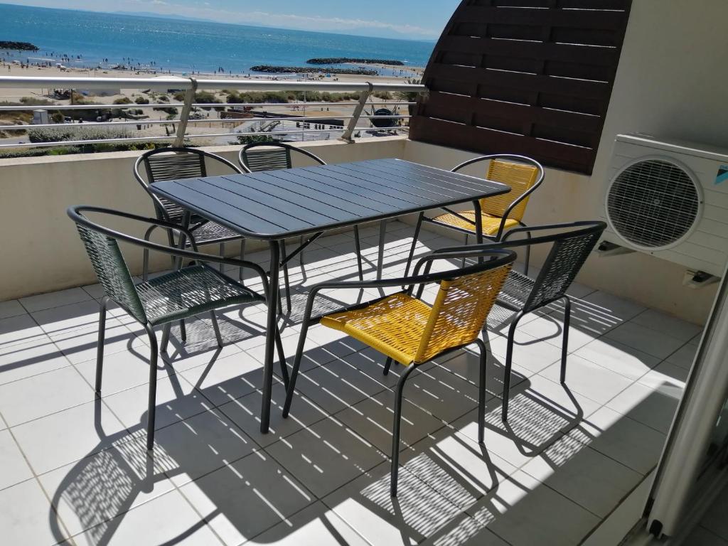 d'une table et de chaises sur un balcon donnant sur la plage. dans l'établissement Bleu du Sud, au Cap d'Agde