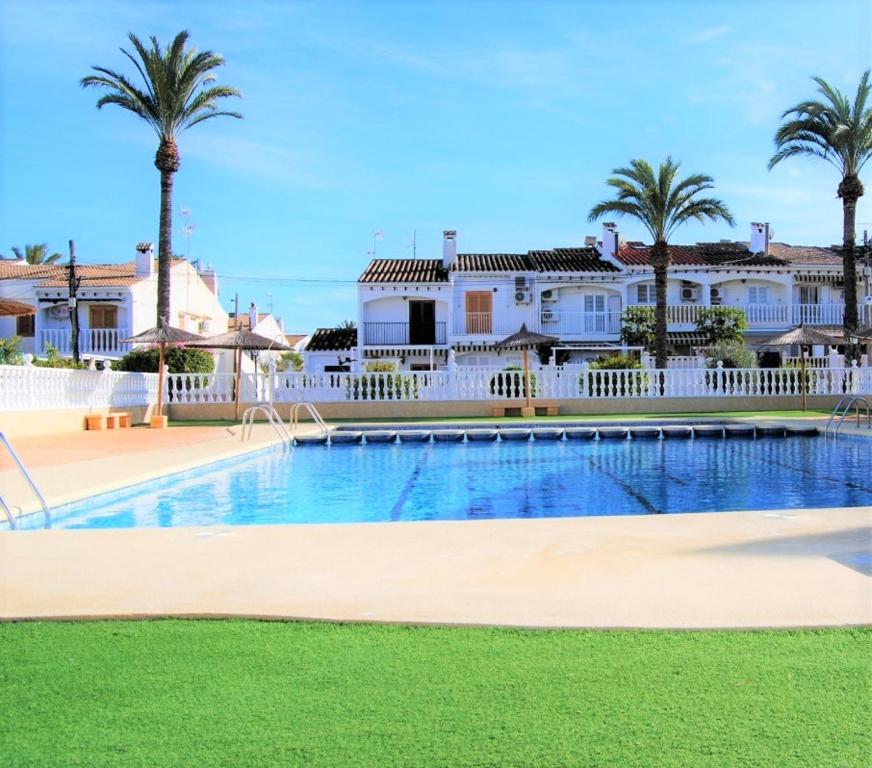 una piscina con palmeras y casas en Casa Ilda (Gran Alacant), en Gran Alacant