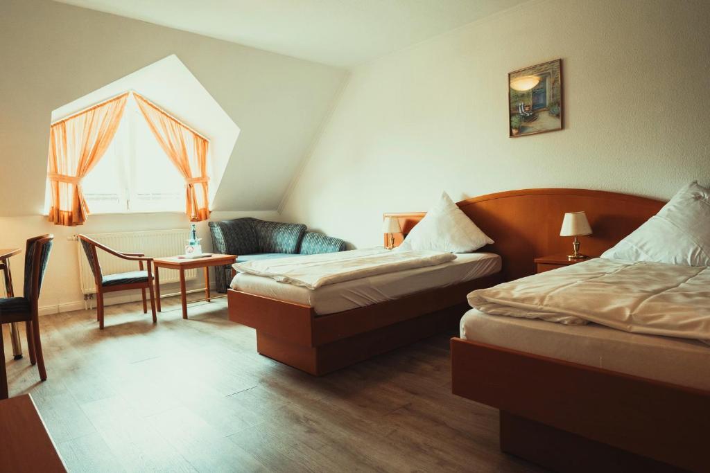 ラシュテーデにあるSchlosspark-Hotel Hof von Oldenburgのベッド2台、テーブルと椅子が備わるホテルルームです。