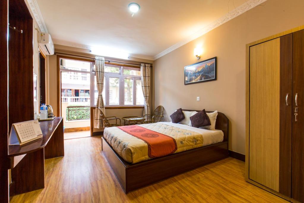 1 dormitorio con cama, escritorio y ventana en Hotel Acme Inn en Katmandú