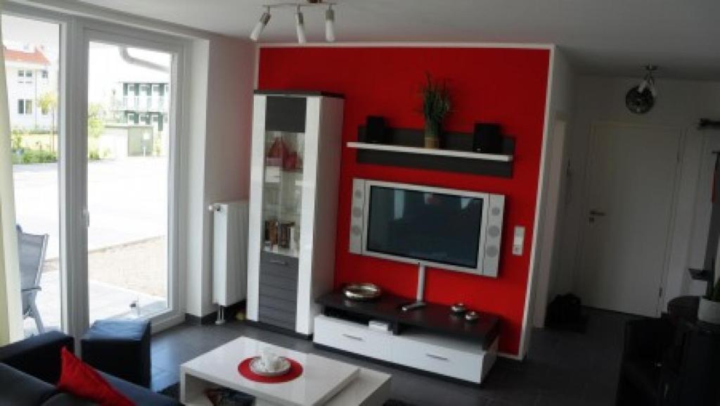 a living room with a red wall with a tv at Ostseebrise 4 - Großenbrode in Großenbrode