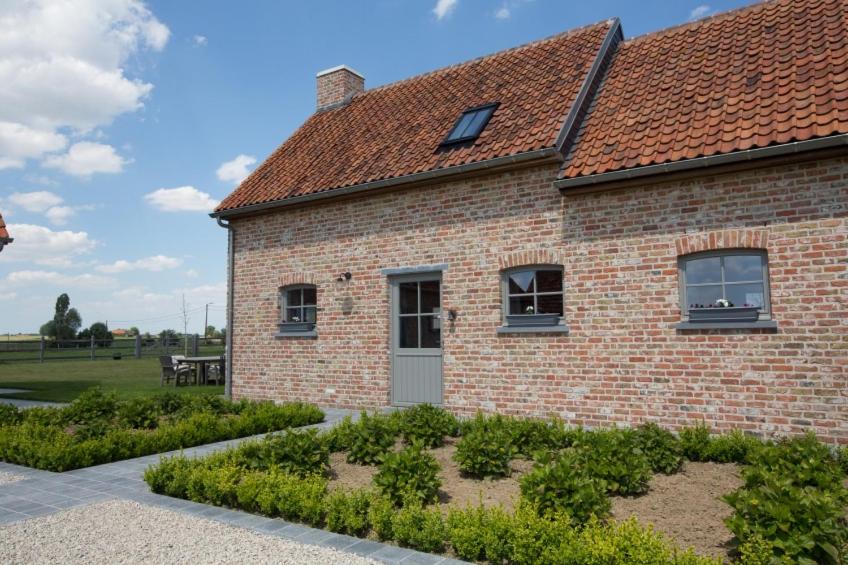 una casa de ladrillo con un jardín delante de ella en Cottage d'Hoge Schure, en Heuvelland