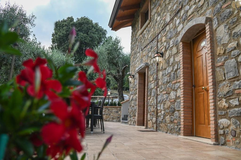 ein Steingebäude mit einer Holztür und roten Blumen in der Unterkunft Il Casale del Barone in San Giovanni a Piro