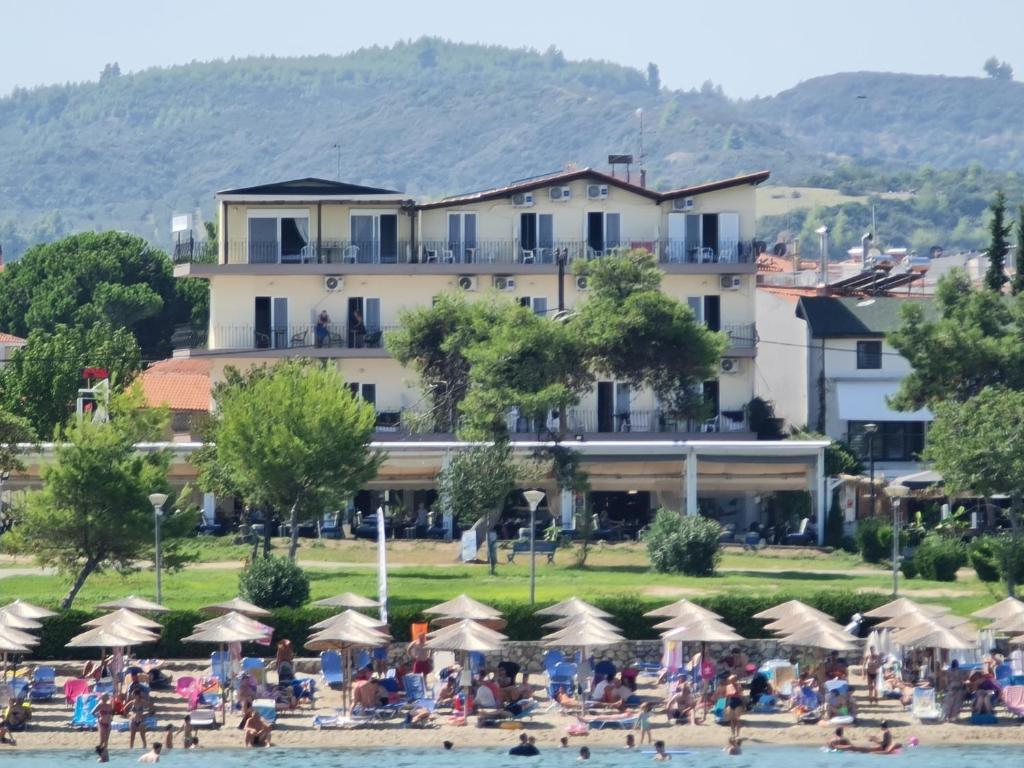 un gruppo di persone sulla spiaggia di fronte a un hotel di Plaza Hotel a Hanioti