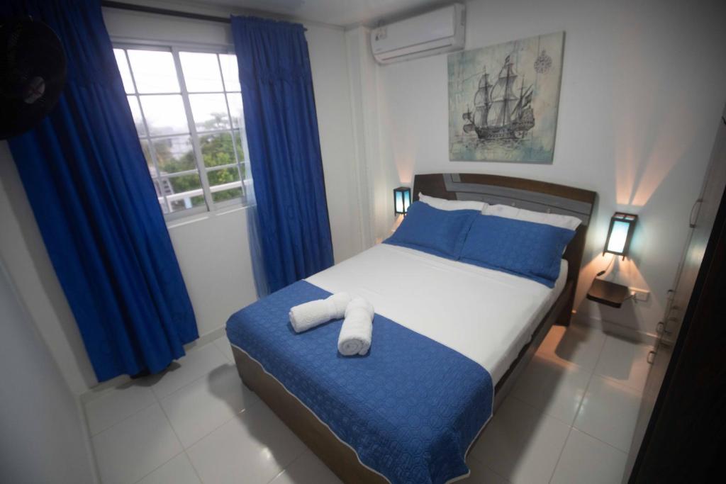 a bedroom with a bed with blue and white sheets at Apartamentos Chalet del Mar in San Andrés