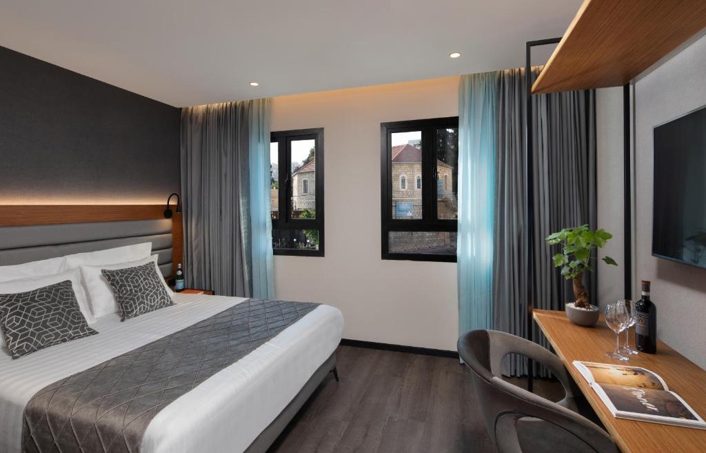 a hotel room with a bed and a desk and windows at The Blend in Nazareth