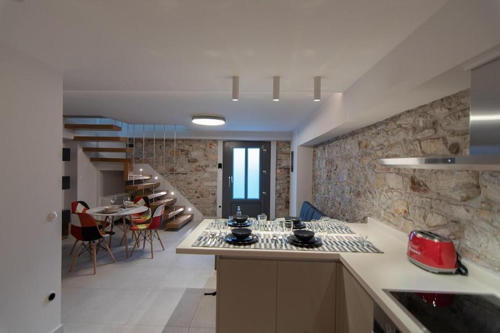 a kitchen and dining room with a stone wall at Villa Samos - Renovated stone villa with private pool- 2 min from the sea! in Samos