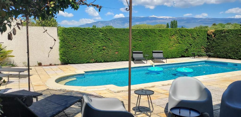 a swimming pool in a yard with chairs around it at Gîte Les Murmures du Ventoux in Mormoiron