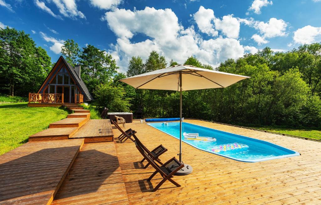 ein Pool mit einem Sonnenschirm und zwei Stühlen sowie ein Pool in der Unterkunft Dosbajka in Małastów