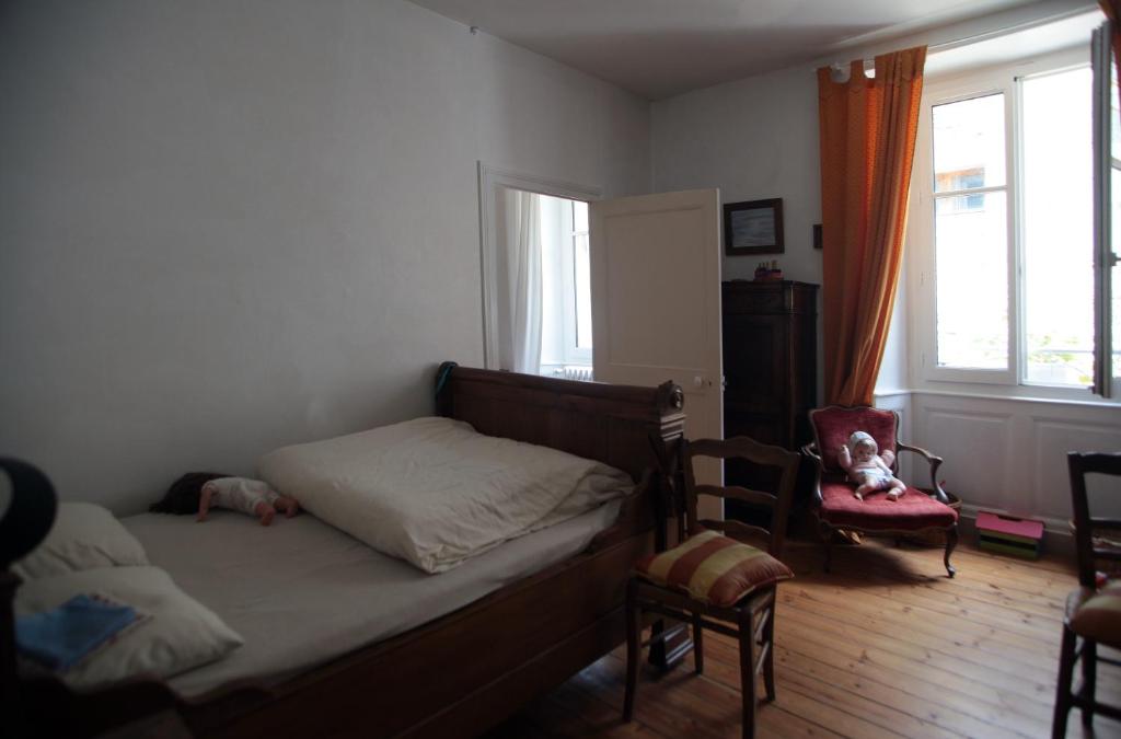 a bedroom with a bed and a chair and a window at Le Magnolia in La Rochefoucauld