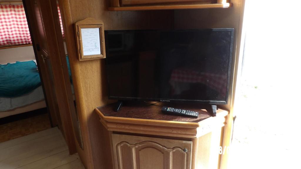 a flat screen tv on a stand in a room at Calme de la campagne in Le Torp-Mesnil