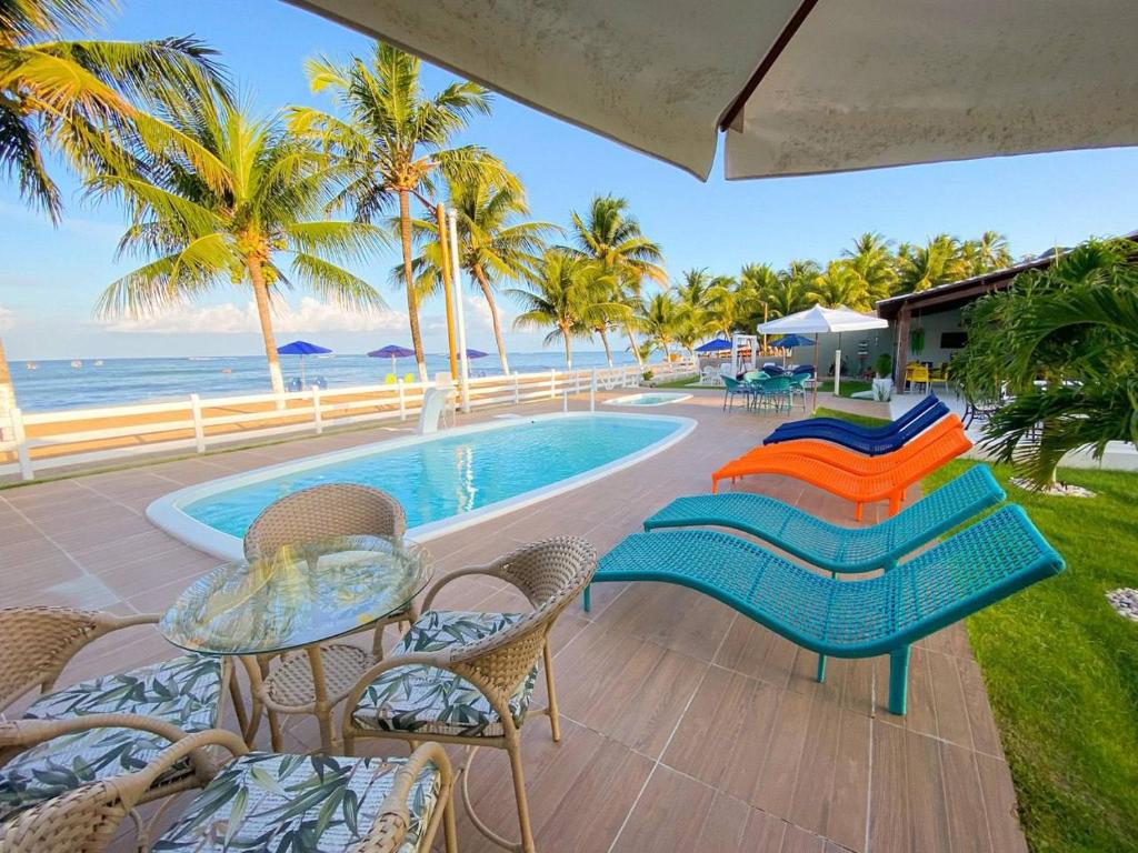 a patio with chairs and a swimming pool and the ocean at Mon Chéri - Pousada Exclusive in Japaratinga