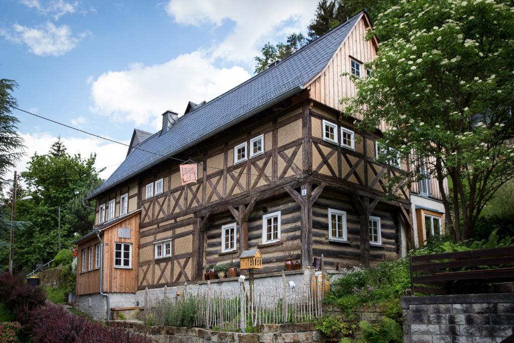 ein altes Holzhaus mit schwarzem Dach in der Unterkunft Kulturdenkmal Umgebinde1657 in Bad Schandau