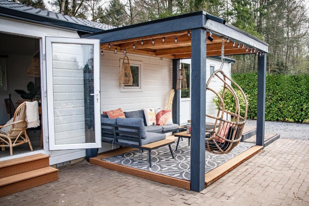 einen Pavillon mit einer Couch auf einer Terrasse in der Unterkunft StayatSas Tiny House Sam in de bossen op de Veluwe! in Epe