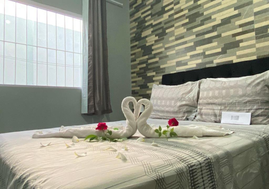 Dois cisnes brancos estão sentados numa cama com rosas. em Casa Serena Jacumã em Jacumã