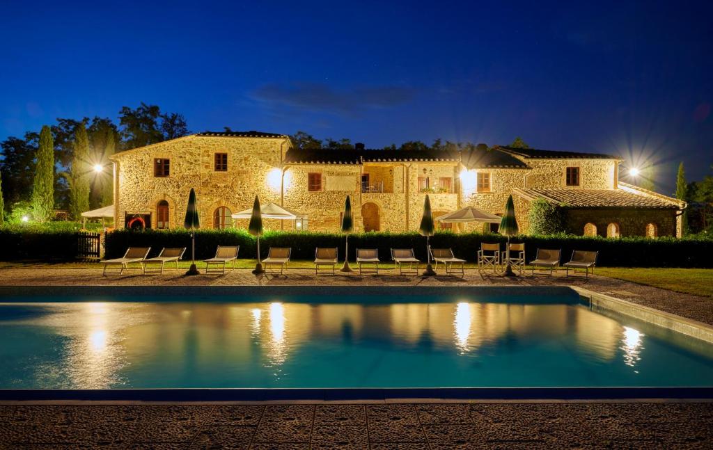 a villa with a swimming pool in front of a building at Agriturismo La Peschiera in Casole dʼElsa