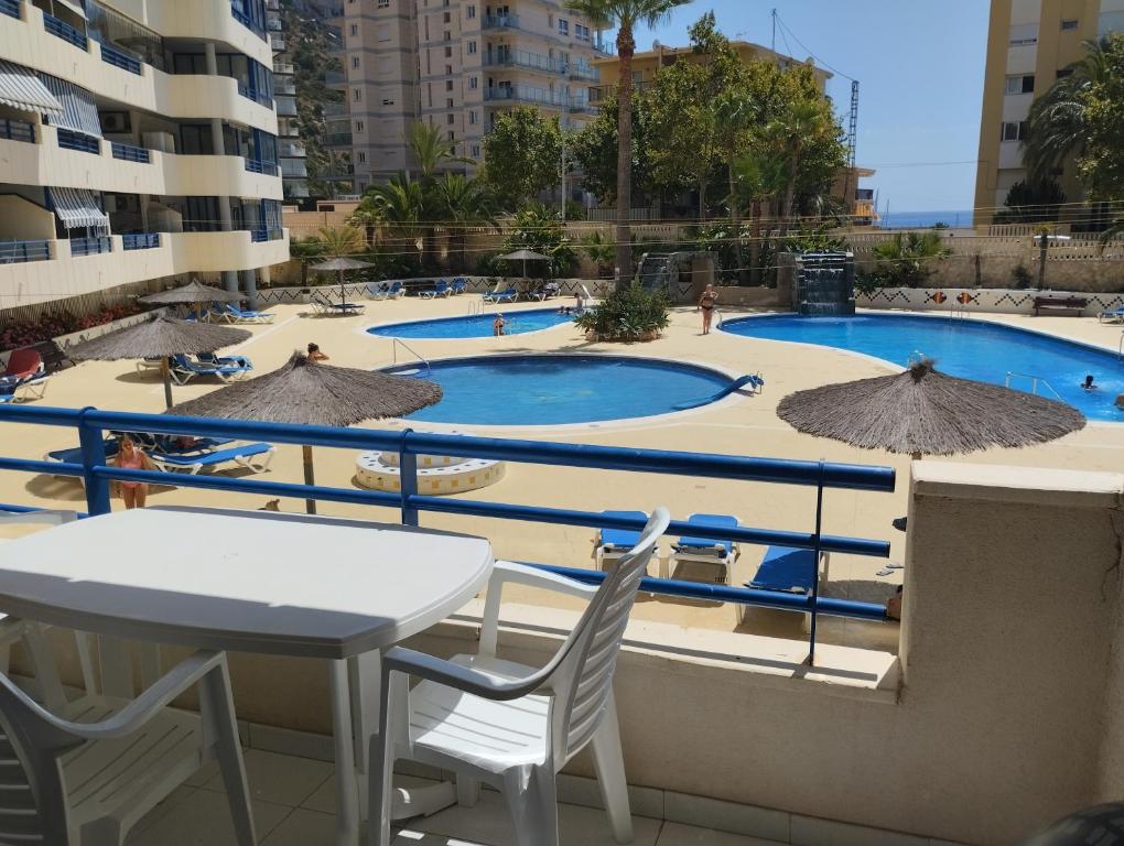 vistas a una piscina con mesas y sombrillas en Appartement équipé CALPE Espagne, 4 couchages, terrasse, piscines, climatisation, garage et WIFI gratuits, en Calpe